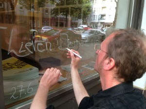 Lieven tekent de openingsuren op het raam van de galerie net voor de opening van de 48 Stunden Neukölln. 
